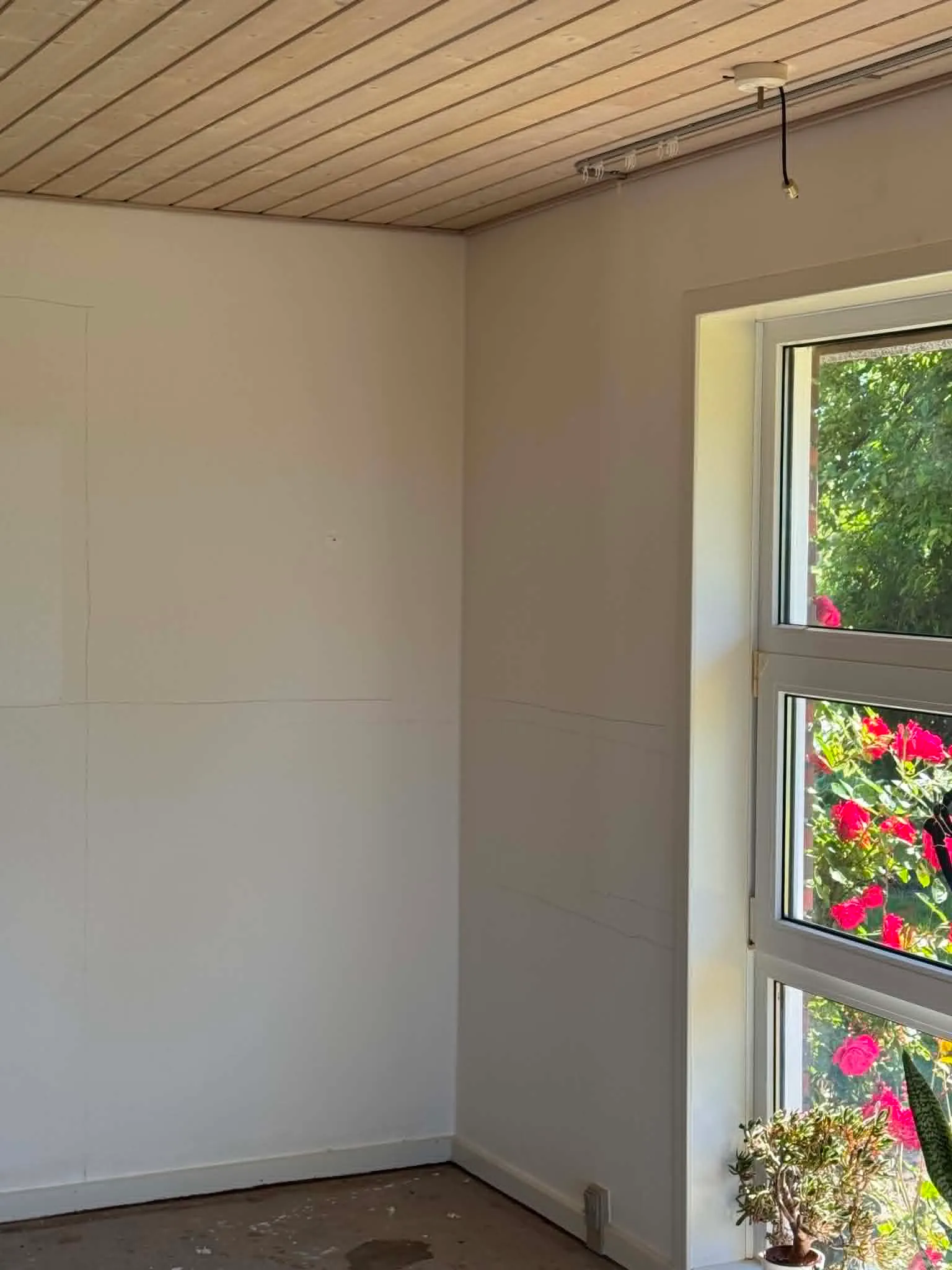Lyst rum under renovering med vindue mod haven